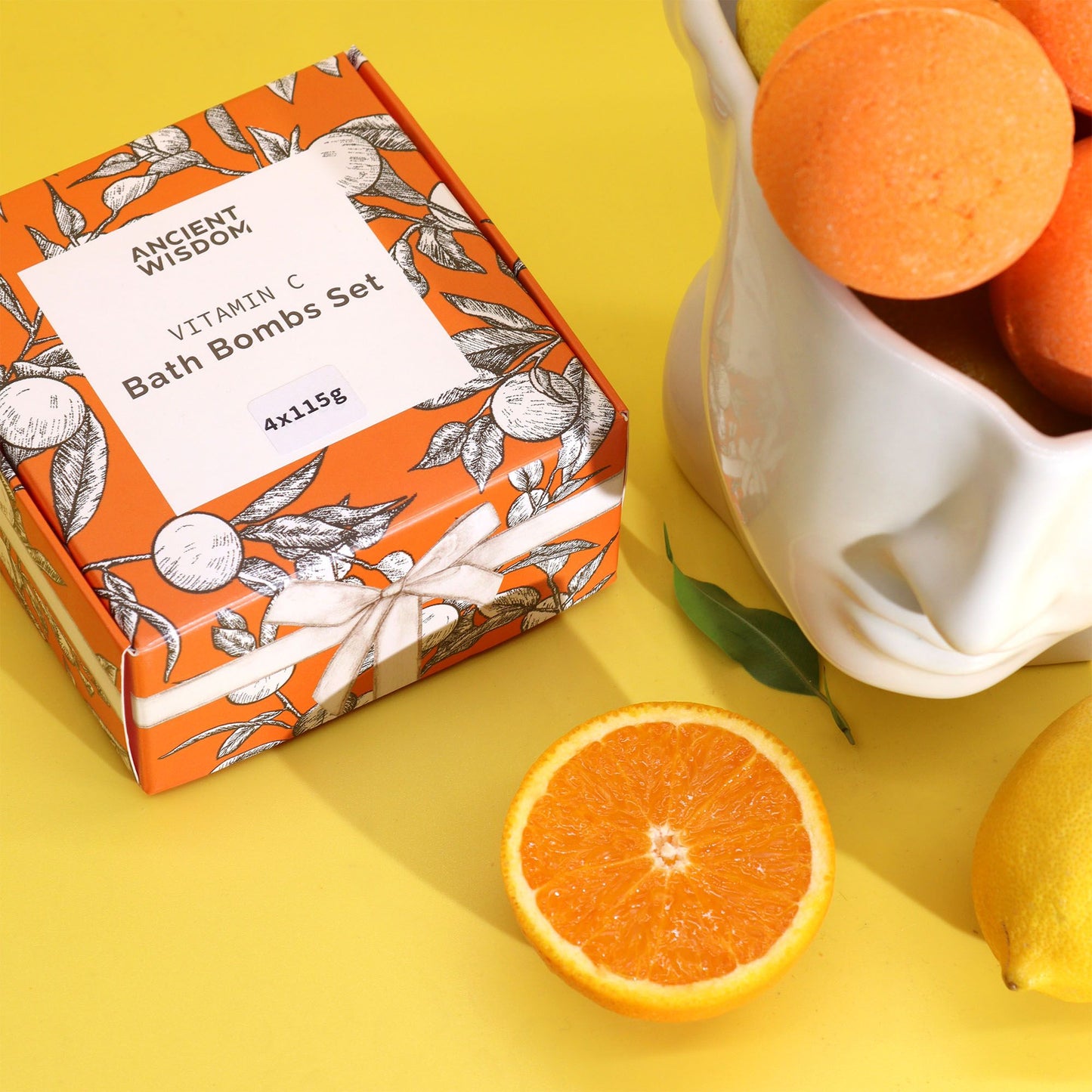 Set de 4 bombas de baño con vitamina C – aromaterapia, en caja naranja con diseño floral, rodeado de cítricos.