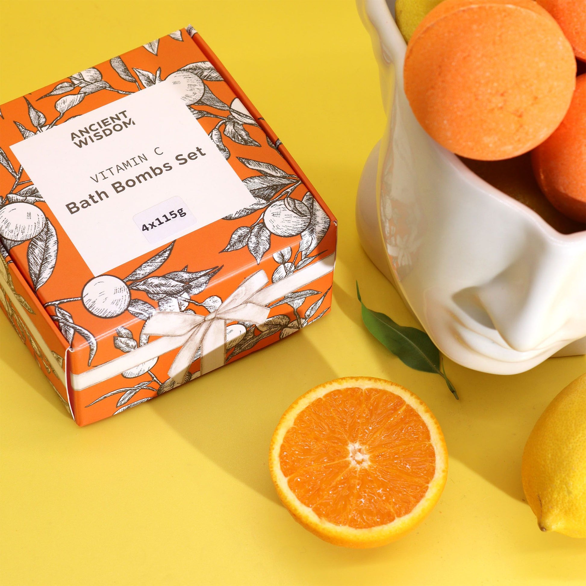 Set de 4 bombas de baño con vitamina C – aromaterapia, en caja naranja con diseño floral, rodeado de cítricos.